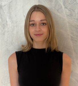 Headshot portrait of Isabelle Duell smiling against a marble backdrop