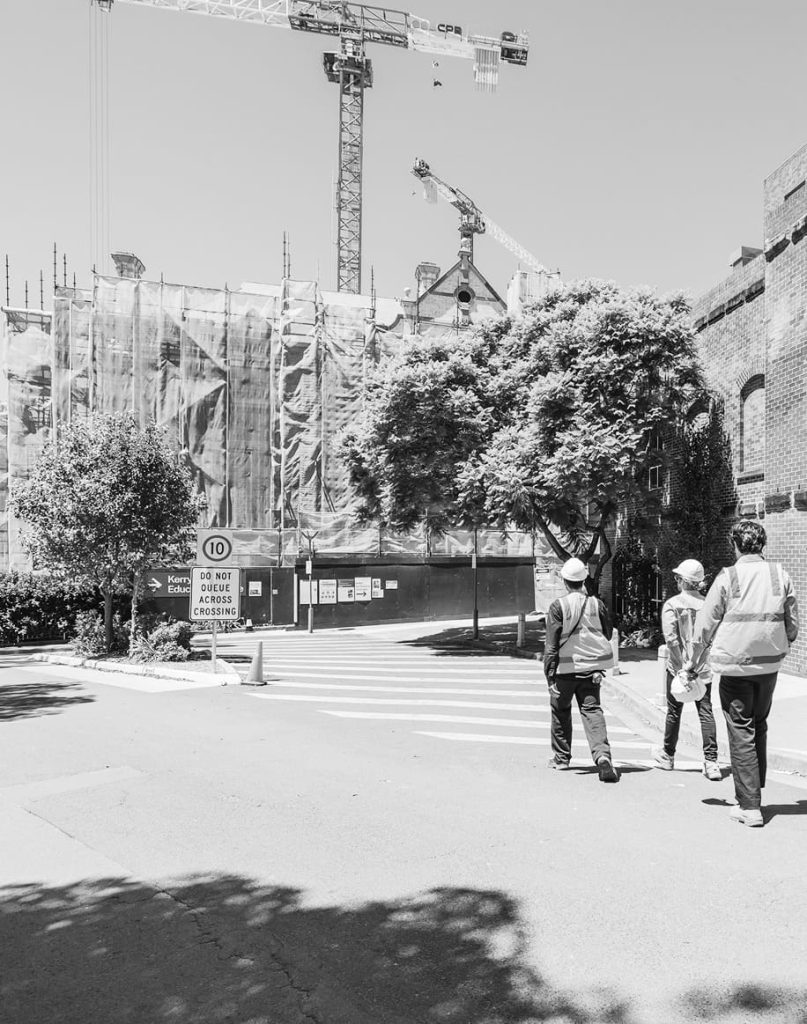 Black and white view of TTW staff near a heritage construction site with tower cranes