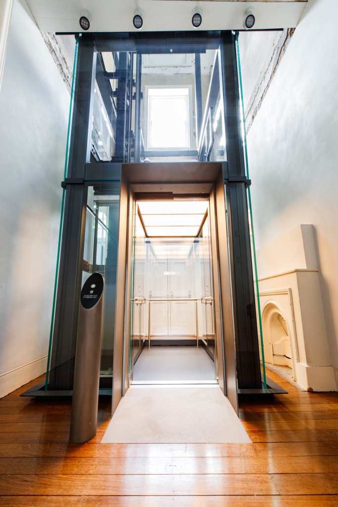 Glass passenger lift enclosure inside Hyde Park Barracks