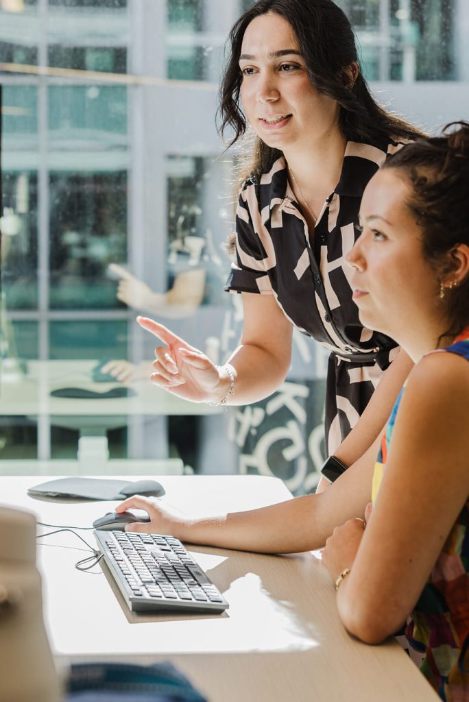 TTW colleague pointing at a screen while helping a coworker at a desk